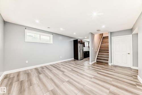This open area features light wood-look flooring, light grey walls, and recessed lighting - 16720 61 Street, Edmonton, AB - Indoor