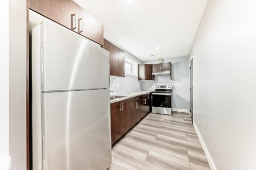 The property features a kitchen with wood cabinetry, light-colored countertops, stainless steel appliances, and light-toned flooring - 16720 61 Street, Edmonton, AB - Indoor Photo Showing Kitchen