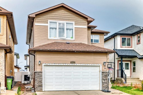 The property features tan siding with white trim, a brown shingled roof, and an attached garage with a white door - 16720 61 Street, Edmonton, AB - Outdoor