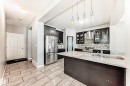 The kitchen features dark cabinetry, stainless steel appliances, a tile backsplash, and an island with a sink and countertop space - 16720 61 Street, Edmonton, AB  - Indoor Photo Showing Kitchen With Upgraded Kitchen 