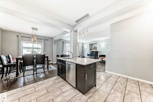 The property features a kitchen island with a stainless steel dishwasher, a dining area with hardwood floors, and a living area with light gray walls - 16720 61 Street, Edmonton, AB - Indoor Photo Showing Other Room