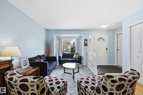 Living area featuring light blue walls, a white front door with a half-moon window, and a bay window providing natural light - 85 Arlington Drive, St. Albert, AB - Indoor