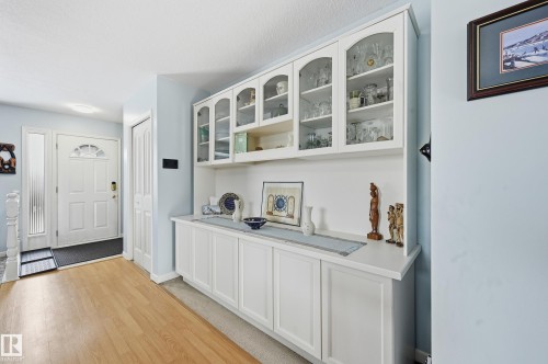The entrance features a white paneled door with an arched glass insert and a sidelight, complemented by light wood flooring - 85 Arlington Drive, St. Albert, AB - Indoor Photo Showing Other Room