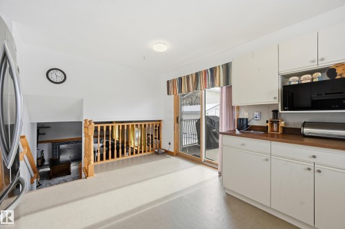 Kitchen area featuring white cabinetry, a built-in microwave, and a sliding glass door providing access to an outdoor area - 85 Arlington Drive, St. Albert, AB - 