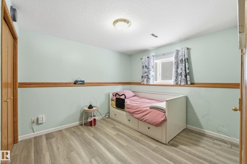 This room features light-colored walls with a wooden accent trim, light wood-style flooring, and a window for natural light - 85 Arlington Drive, St. Albert, AB - Indoor
