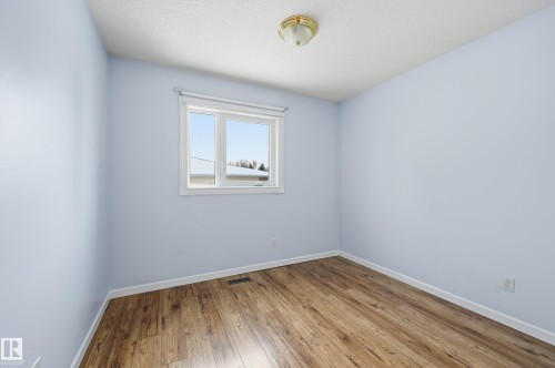 The room features light blue walls, wood-style flooring, a window providing natural light, and a ceiling light fixture - 85 Arlington Drive, St. Albert, AB - Indoor Photo Showing Other Room
