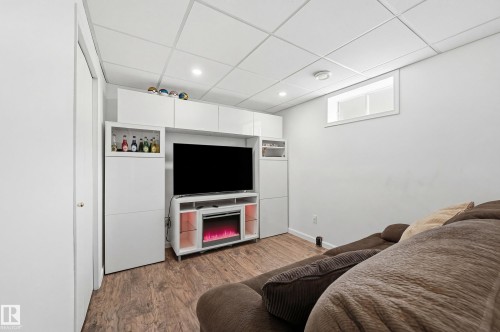 This room features wood-look flooring, a white drop ceiling with recessed lighting, and a window providing natural light - 85 Arlington Drive, St. Albert, AB - Indoor