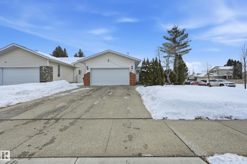 The property features a concrete driveway leading to an attached garage, with a partial brick facade accenting the front entrance - 85 Arlington Drive, St. Albert, AB - Outdoor