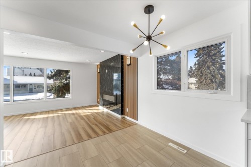 Living space featuring light-toned flooring, large windows, and a modern light fixture - 13116 128A Avenue, Edmonton, AB - Indoor