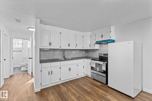 The kitchen features white cabinetry, a stainless steel range, and a white refrigerator - 13116 128A Avenue, Edmonton, AB - Indoor Photo Showing Kitchen