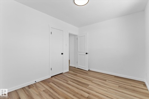 This room features light wood-look flooring, white walls, and a white ceiling with a flush-mount light fixture - 13116 128A Avenue, Edmonton, AB - Indoor Photo Showing Other Room