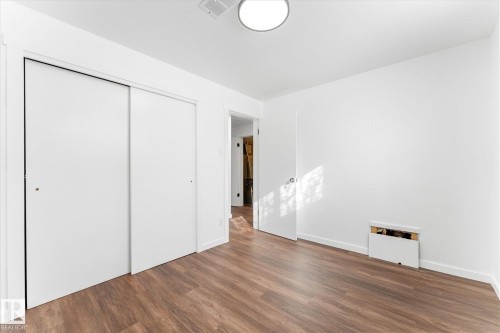 This room features hardwood style flooring, white walls, and a ceiling light fixture - 13116 128A Avenue, Edmonton, AB - Indoor Photo Showing Other Room