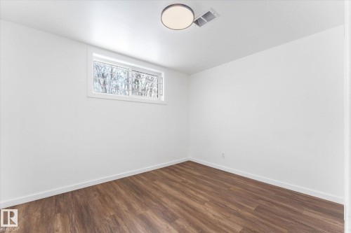 Room featuring light wood-look flooring, white walls, and a window with a view of trees - 13116 128A Avenue, Edmonton, AB - Indoor Photo Showing Other Room