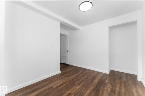 This room features wood-look flooring, white walls, and a contemporary flush-mount ceiling light fixture - 13116 128A Avenue, Edmonton, AB - Indoor Photo Showing Other Room