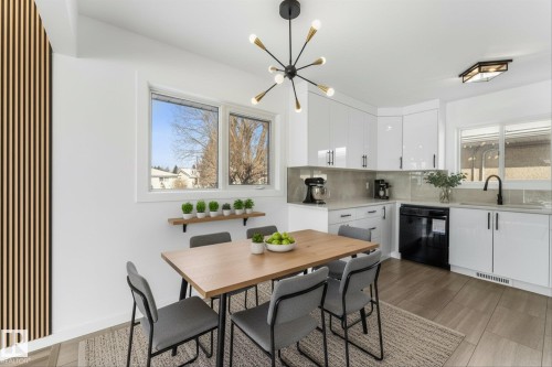 This kitchen and dining area features white cabinetry with black handles, a black dishwasher, and a black sink faucet - 13116 128A Avenue, Edmonton, AB - Indoor Photo Showing Dining Room