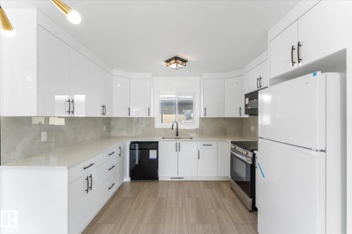 The kitchen features white cabinetry, light countertops, a white refrigerator, a black dishwasher, and a stainless steel oven - 13116 128A Avenue, Edmonton, AB - Indoor Photo Showing Kitchen With Upgraded Kitchen