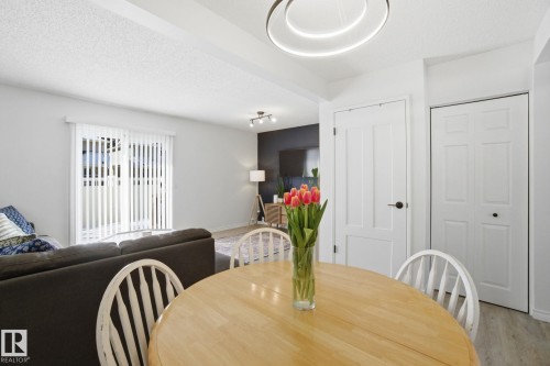 Bright dining area with a round wooden table, white chairs, and a contemporary ceiling light fixture - 29 9619 180 Street, Edmonton, AB - Indoor Photo Showing Dining Room