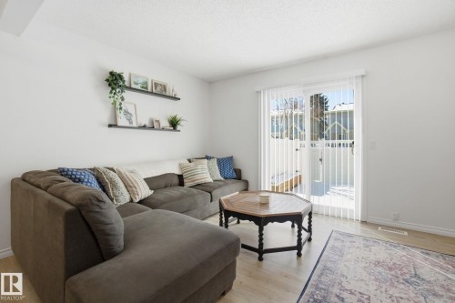The living area features light-colored flooring, white walls, and a sliding glass door providing external views and natural light - 29 9619 180 Street, Edmonton, AB - Indoor Photo Showing Living Room