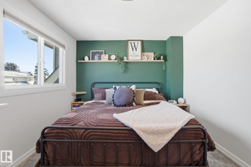 This bedroom features a vibrant accent wall, a large window providing natural light, and a textured ceiling - 29 9619 180 Street, Edmonton, AB - Indoor Photo Showing Bedroom