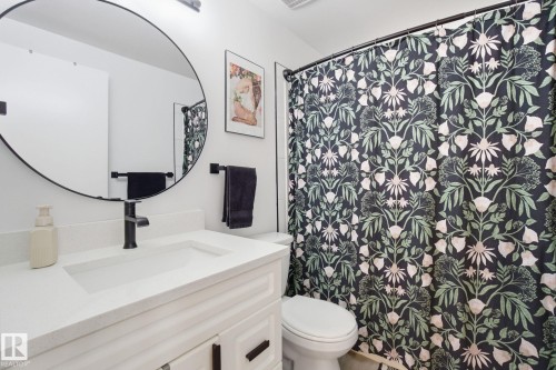 Bathroom vanity with a white countertop and a round mirror - 29 9619 180 Street, Edmonton, AB - Indoor Photo Showing Bathroom