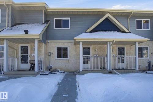 The property features a charming exterior with light blue siding and light stucco, complemented by white window frames and a covered front porch - 29 9619 180 Street, Edmonton, AB - Outdoor With Deck Patio Veranda With Facade