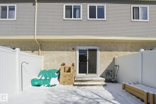 The property features a private outdoor area with a white privacy fence and a sliding glass door providing direct access to the interior - 29 9619 180 Street, Edmonton, AB - Outdoor With Exterior