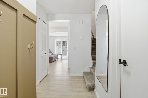 Entryway featuring light-toned flooring, a mirrored accent, and a view into an open living area with sliding glass doors - 29 9619 180 Street, Edmonton, AB - Indoor Photo Showing Other Room