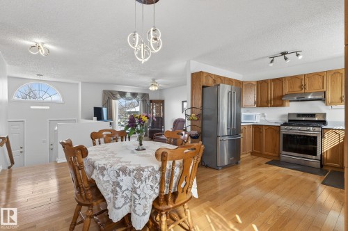 This property features an open-concept layout with hardwood flooring, a kitchen with wooden cabinetry and stainless steel appliances, and a dining area - 22 Riverpointe, Fort Saskatchewan, AB - Indoor