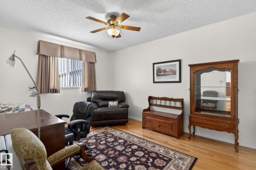This room features hardwood flooring, a window with vertical blinds and drapes, and a ceiling fan - 22 Riverpointe, Fort Saskatchewan, AB - Indoor Photo Showing Living Room