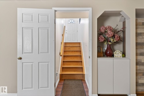 Entryway featuring hardwood flooring, a wooden staircase, and a built-in storage cabinet with an arched alcove - 22 Riverpointe, Fort Saskatchewan, AB - Indoor Photo Showing Other Room
