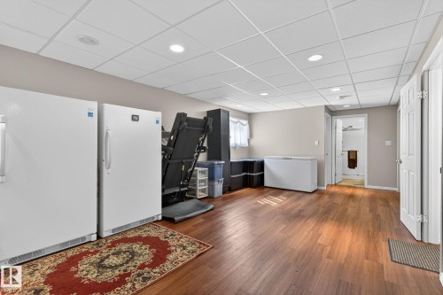 This versatile room features warm-toned hardwood flooring, recessed lighting, and a drop ceiling - 22 Riverpointe, Fort Saskatchewan, AB - Indoor Photo Showing Other Room