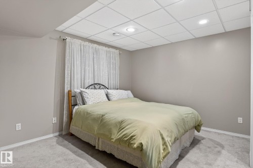 This room features light gray walls, a textured drop ceiling with recessed lighting, and soft gray carpeting - 22 Riverpointe, Fort Saskatchewan, AB - Indoor Photo Showing Bedroom