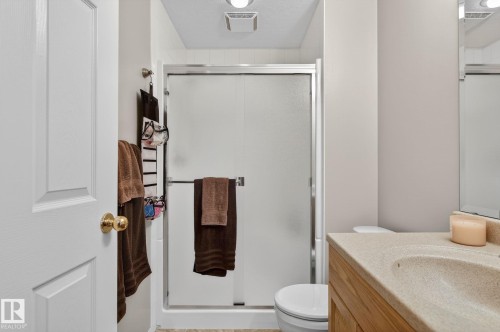 The bathroom features a shower with a sliding glass door, a vanity with a light-colored countertop, and a toilet - 22 Riverpointe, Fort Saskatchewan, AB - Indoor Photo Showing Bathroom
