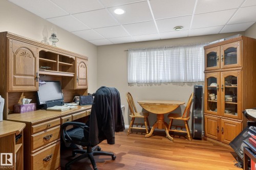 This versatile room features warm-toned flooring, neutral painted walls, and a drop ceiling - 22 Riverpointe, Fort Saskatchewan, AB - Indoor Photo Showing Office