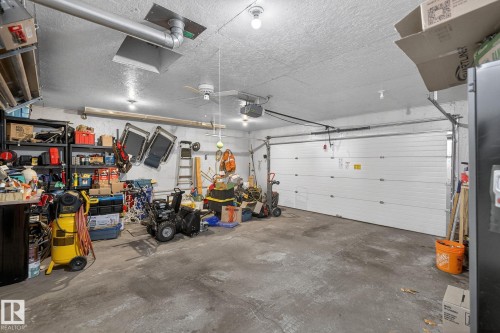 The property features a garage with a concrete floor, overhead lighting, and a white sectional garage door - 22 Riverpointe, Fort Saskatchewan, AB - Indoor Photo Showing Garage