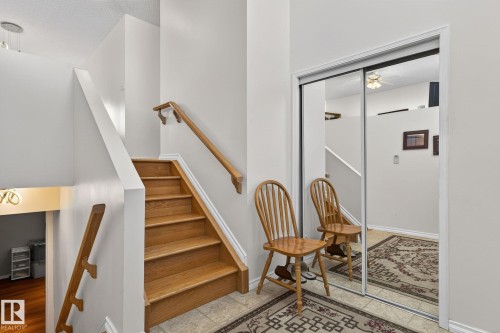 Entryway featuring wood stairs with a handrail, light-colored walls, and mirrored closet doors - 22 Riverpointe, Fort Saskatchewan, AB - Indoor Photo Showing Other Room
