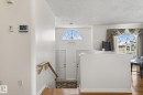 The property features a bright entranceway with a transom window above the entry doors, hardwood flooring on the main level, and a staircase with a wooden handrail - 22 Riverpointe, Fort Saskatchewan, AB  - Indoor Photo Showing Other Room 
