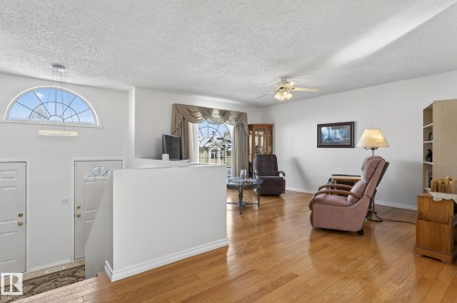 Living area featuring hardwood flooring, a ceiling fan, and large windows with arched transoms providing natural light - 22 Riverpointe, Fort Saskatchewan, AB - Indoor Photo Showing Other Room