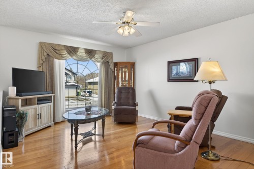 This living area features hardwood floors, a large arched window with drapes, and a ceiling fan - 22 Riverpointe, Fort Saskatchewan, AB - Indoor Photo Showing Other Room