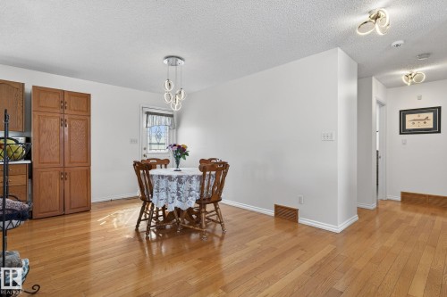 The property features hardwood floors, a white door with decorative glass, and a modern ceiling light fixture - 22 Riverpointe, Fort Saskatchewan, AB - Indoor Photo Showing Dining Room