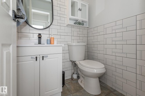 This powder room features a vanity with a white countertop and cabinet storage, a contemporary sink with a matte black faucet, and a toilet - 8326 157 Avenue, Edmonton, AB - Indoor Photo Showing Bathroom