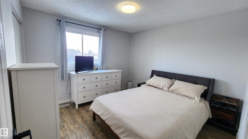 The room features light gray walls, a window with curtains, and a ceiling light fixture - 8326 157 Avenue, Edmonton, AB - Indoor Photo Showing Bedroom