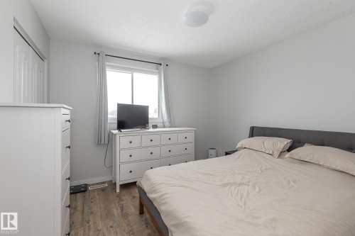 The property features durable wood-style flooring, a window with curtains, and a ceiling light fixture - 8326 157 Avenue, Edmonton, AB - Indoor Photo Showing Bedroom