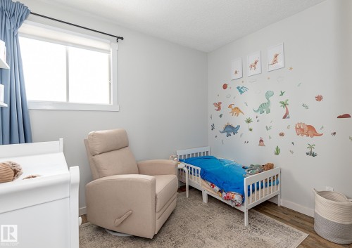 This room features a window with a curtain rod and blue drapes, light-colored walls, and wood-look flooring - 8326 157 Avenue, Edmonton, AB - Indoor Photo Showing Bedroom