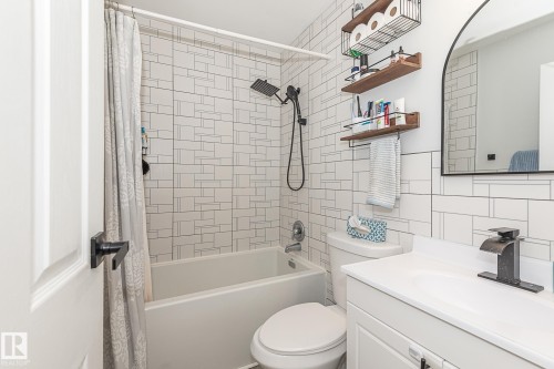 Bathroom featuring a shower/tub combination with white subway tile surround, a white vanity with a single sink, and an arched mirror - 8326 157 Avenue, Edmonton, AB - Indoor Photo Showing Bathroom