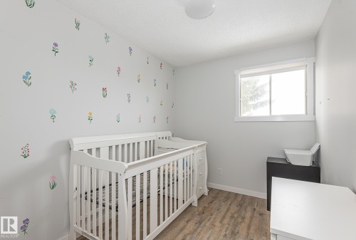 This room features light-toned walls, a window with white trim, and wood-style flooring - 8326 157 Avenue, Edmonton, AB - Indoor
