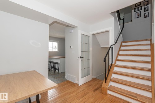 The property features hardwood floors, a staircase with wooden treads and a black metal railing, and a doorway with a decorative glass door - 8326 157 Avenue, Edmonton, AB - Indoor Photo Showing Other Room
