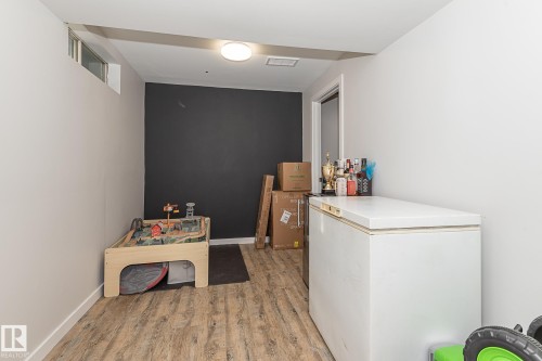 This versatile room features light wood-look flooring, a dark accent wall, and a window - 8326 157 Avenue, Edmonton, AB - Indoor Photo Showing Other Room