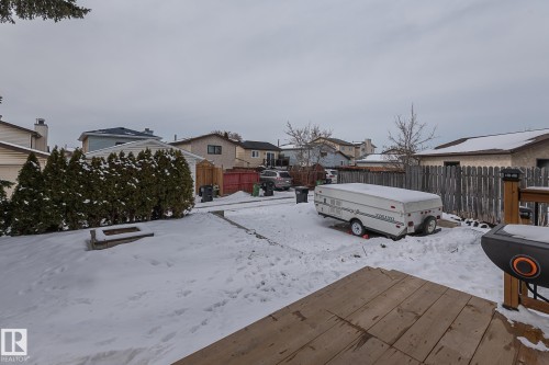 The property features a spacious backyard with a wooden deck, a paved area, and mature evergreen shrubs - 8326 157 Avenue, Edmonton, AB - Outdoor