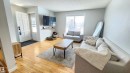 The living area features hardwood flooring, a large window providing natural light, and a clean, light-colored wall finish - 8326 157 Avenue, Edmonton, AB  - Indoor Photo Showing Living Room 